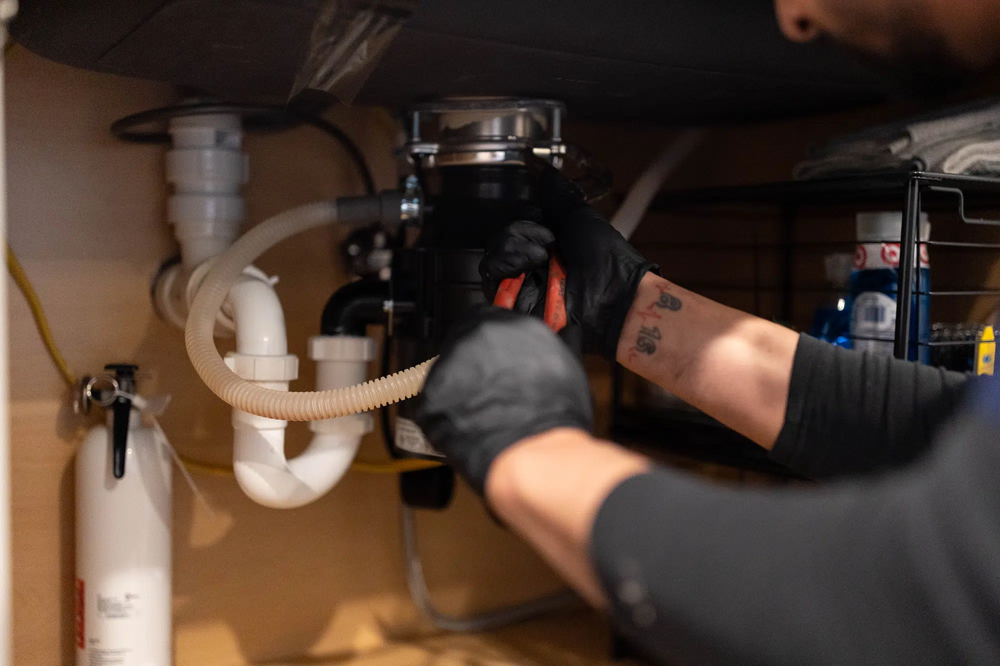 Technician servicing garbage disposal in residential home in Knoxville, TN.