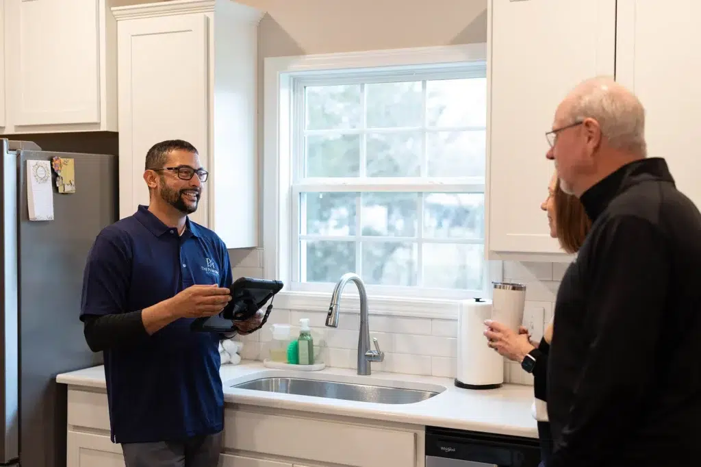 Technician smiling and talking to customers in residential kitchen in Knoxville, TN.