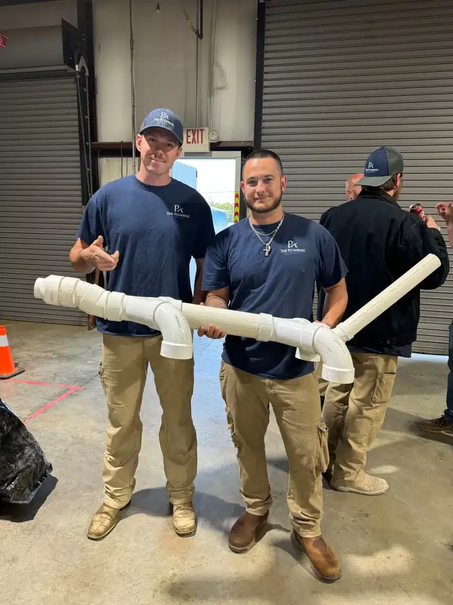 Two team members holding a large pipe creation during a Winning Wednesday challenge