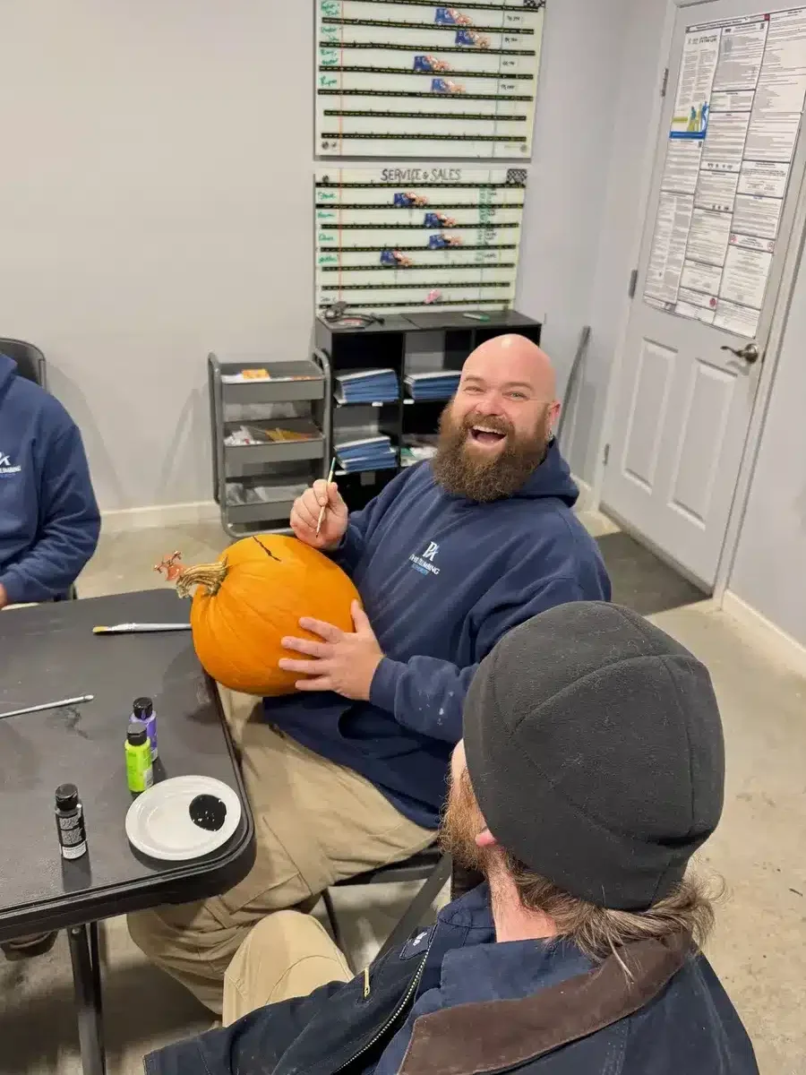 Two team members showing off their pumpkin-carving progress during Winning Wednesday