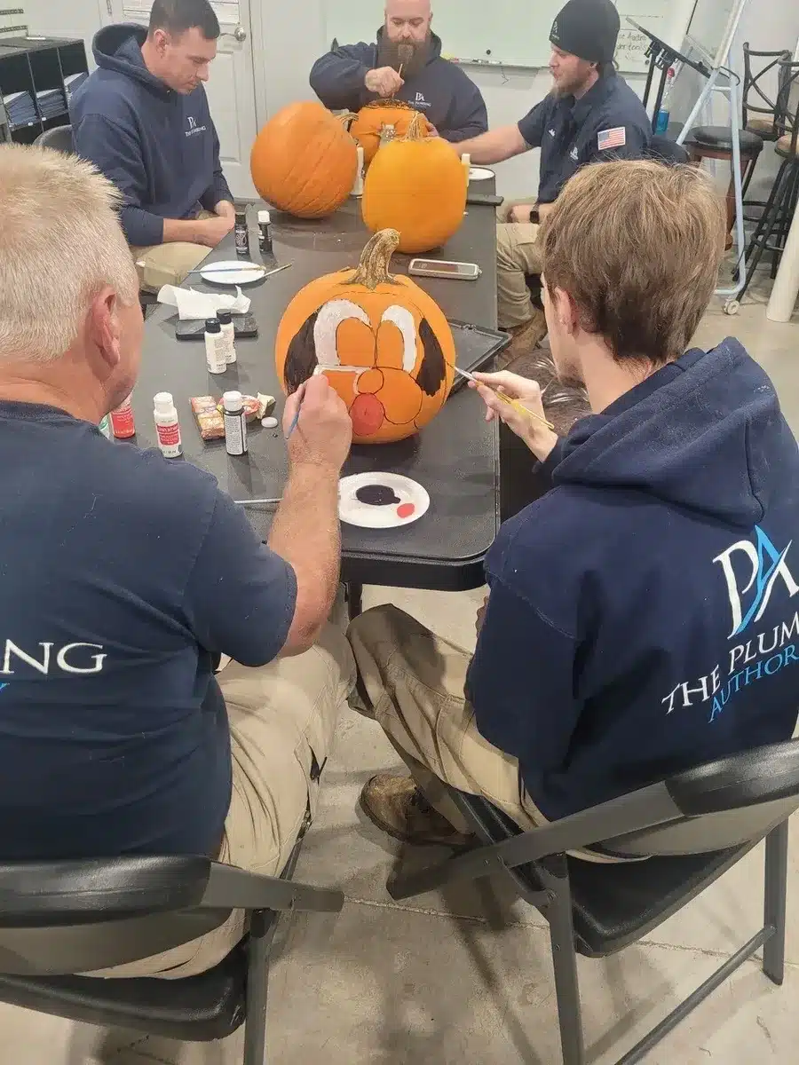Employees painting pumpkins side by side during a Winning Wednesday activity