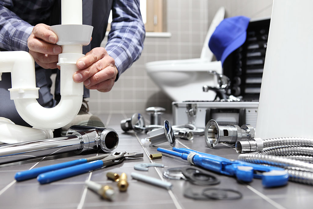 plumber fixing p trap and toilet in bathroom